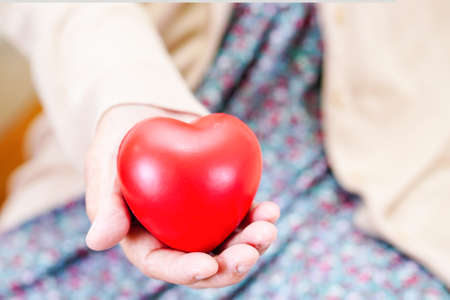 Asian elder senior woman patient holding red heart in hospital.の写真素材