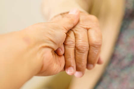 Caregiver holding hands Asian elderly woman patient, help and care in hospital.