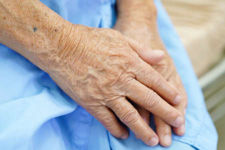 Asian elder senior woman patient put holding hands on her
lap alone for waiting her family.の写真素材
