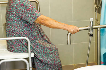 Asian elderly old woman patient use toilet support rail in bathroom, handrail safety grab bar, security in nursing hospital.の写真素材