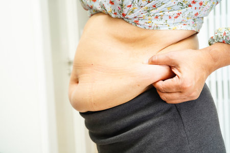 Asian woman show fat belly big size overweight and obesity at office.の写真素材