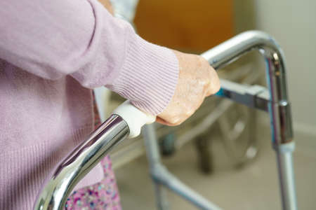Asian elderly woman disability patient walk with walker in nursing hospital, medical concept.の写真素材