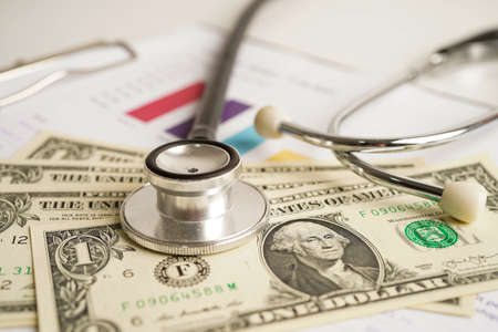 Stethoscope and US dollar banknotes on chart or graph paper, Financial, account, statistics and business data  medical health concept.の写真素材