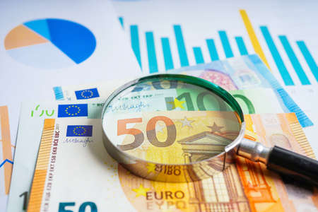 Magnifying glass on EURO banknotes and graph, finance business trade concept.の写真素材