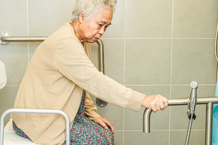 Asian elderly old woman patient use toilet support rail in bathroom, handrail safety grab bar, security in nursing hospital.の写真素材