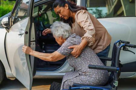 Caregiver help Asian elderly woman disability patient get in her car, medical concept.の写真素材