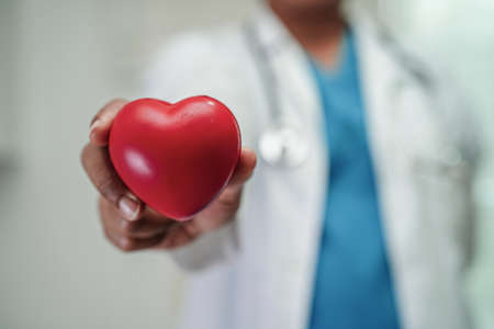 Asian woman doctor holding red heart for health in hospital.の写真素材