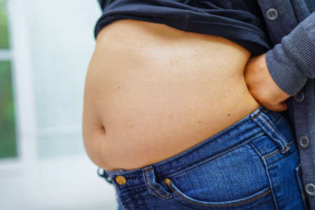 Asian woman show fat belly big size overweight and obesity at office.の写真素材