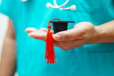 Asian woman doctor holding graduation hat in hospital, Medical education concept.の写真素材