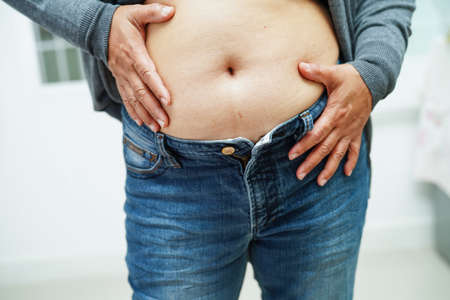 Asian woman show fat belly big size overweight and obesity at office.の写真素材