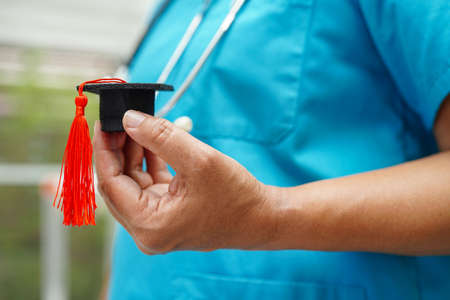 Asian woman doctor holding graduation hat in hospital, Medical education concept.の写真素材