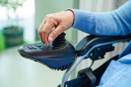 Asian elderly woman disability patient sitting on electric wheelchair in park, medical concept.の写真素材