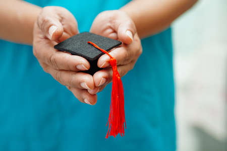 Asian woman doctor holding graduation hat in hospital, Medical education concept.の写真素材