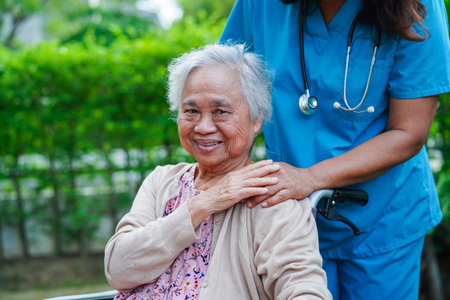 Doctor help Asian elderly woman disability patient sitting on wheelchair in park, medical concept.の写真素材