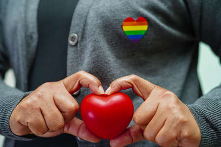Asian woman holding red hert with rainbow flag, LGBT symbol rights and gender equality, LGBT Pride Month in June.の写真素材