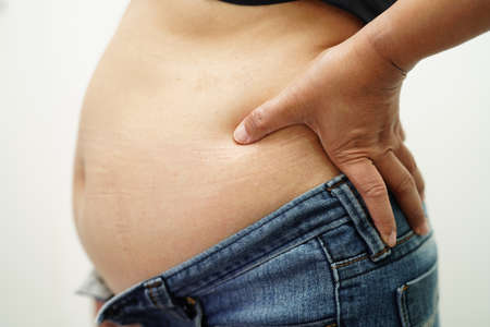 Asian woman show fat belly big size overweight and obesity at office.の写真素材