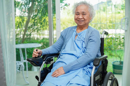 Asian elderly woman disability patient sitting on electric wheelchair in park, medical concept.の写真素材