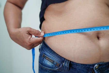 Asian woman show fat belly big size overweight and obesity at office.
