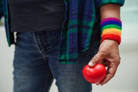 Asian woman holding red hert with rainbow flag, LGBT symbol rights and gender equality, LGBT Pride Month in June.の写真素材