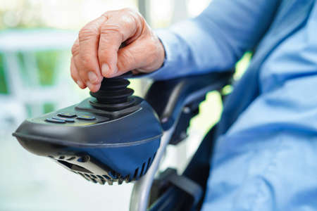 Asian elderly woman disability patient sitting on electric wheelchair in park, medical concept.の写真素材