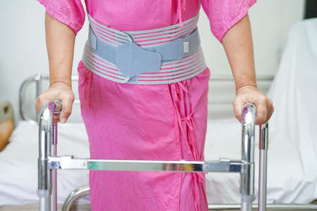 Asian senior pain back wearing elastic support belt with walker.の写真素材