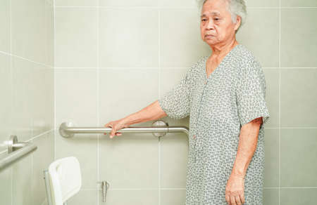 Asian elderly old woman patient use toilet support rail in bathroom, handrail safety grab bar, security in nursing hospital.の写真素材