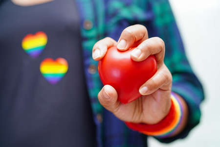 Asian woman holding red hert with rainbow flag, LGBT symbol rights and gender equality, LGBT Pride Month in June.の写真素材