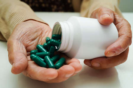 Asian elderly woman holding pill drug in hand, strong healthy medical concept.の写真素材
