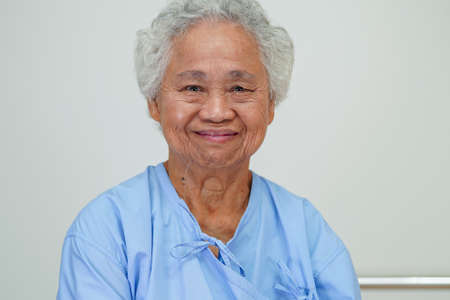 Asian elder senior woman patient sitting and smile face with happy on bed in hospital.の写真素材