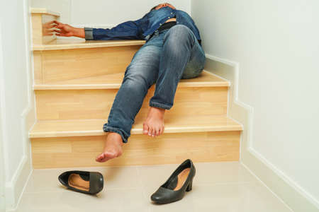 Asian business woman pain ankle, foot with leg cramp and fall down the stairs because slippery surfaces in office.の写真素材