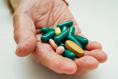 Asian elderly woman holding pill drug in hand, strong healthy medical concept.の写真素材