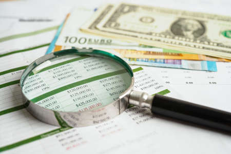 Magnifying glass on US dollar and EURO banknotes and graph, finance business trade concept.の写真素材