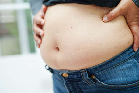 Asian woman show fat belly big size overweight and obesity at office.