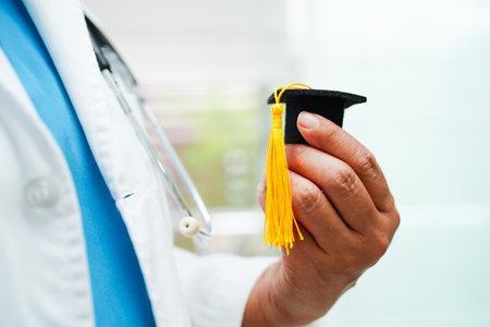 Asian woman doctor holding graduation hat in hospital, Medical education concept.の写真素材