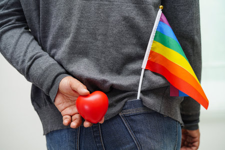 Asian woman holding red hert with rainbow flag, LGBT symbol rights and gender equality, LGBT Pride Month in June.の写真素材