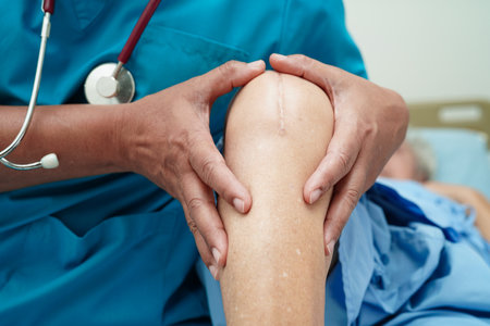 Doctor checking Asian elderly woman patient with scar knee replacement surgery in hospital.の写真素材