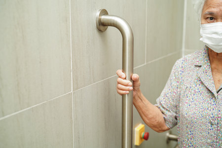 Asian woman patient use toilet support rail in bathroom, handrail safety grab bar, security in nursing hospital.の写真素材