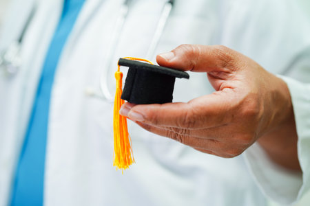 Asian woman doctor holding graduation hat in hospital, Medical education concept.の写真素材