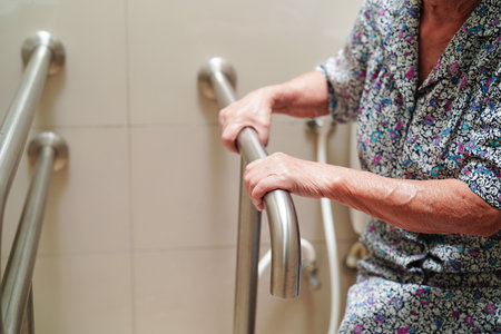 Asian elderly old woman patient use toilet support rail in bathroom, handrail safety grab bar, security in nursing hospital.の写真素材