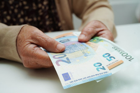Retired elderly woman holding Euro banknotes money and worry about monthly expenses and treatment fee payment.の写真素材