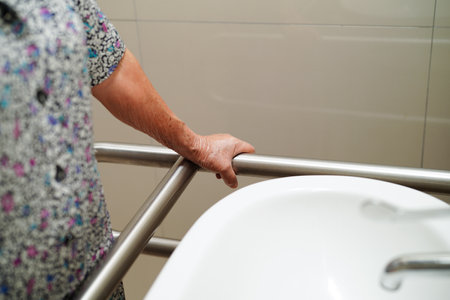 Asian woman patient use toilet support rail in bathroom, handrail safety grab bar, security in nursing hospital.の写真素材