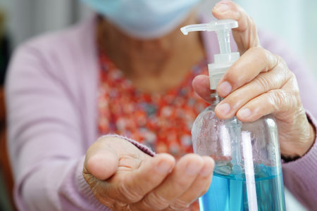 Asian senior woman press blue alcohol sanitizer gel for washing hand protect infection coronavirus.の写真素材