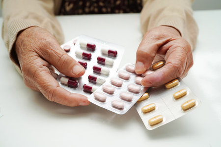 Asian elderly woman holding pill drug in hand, strong healthy medical concept.の写真素材