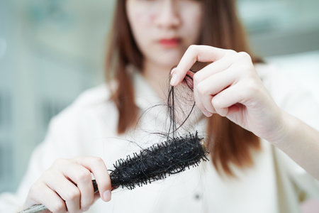 Asian woman have problem with long hair loss attach to comb brush.