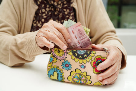 Retired elderly woman counting coins money and worry about monthly expenses and treatment fee payment.の写真素材