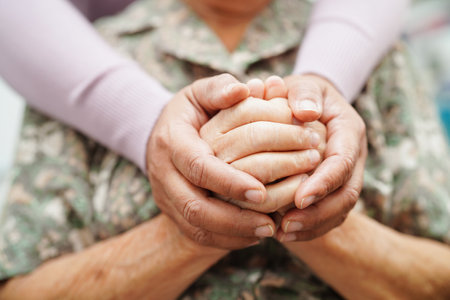Caregiver holding hands Asian elderly woman patient, help and care in hospital.の写真素材
