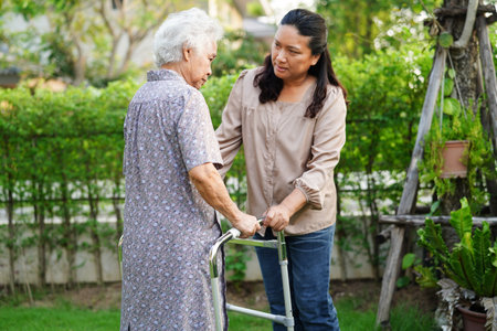 Caregiver help Asian elderly woman disability patient sitting on wheelchair in park, medical concept.の写真素材