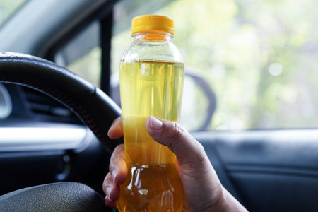 Asian woman driver hold cold water for drink in car, dangerous and risk an accident.の写真素材