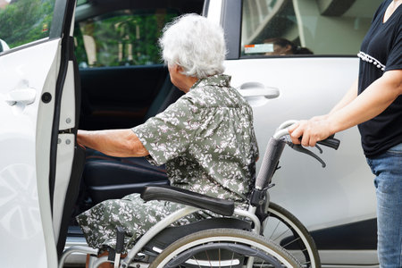 Caregiver help Asian elderly woman disability patient get in her car, medical concept.の写真素材