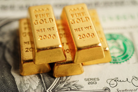 Gold bars on US dollar banknote money, finance trading investment business currency concept.